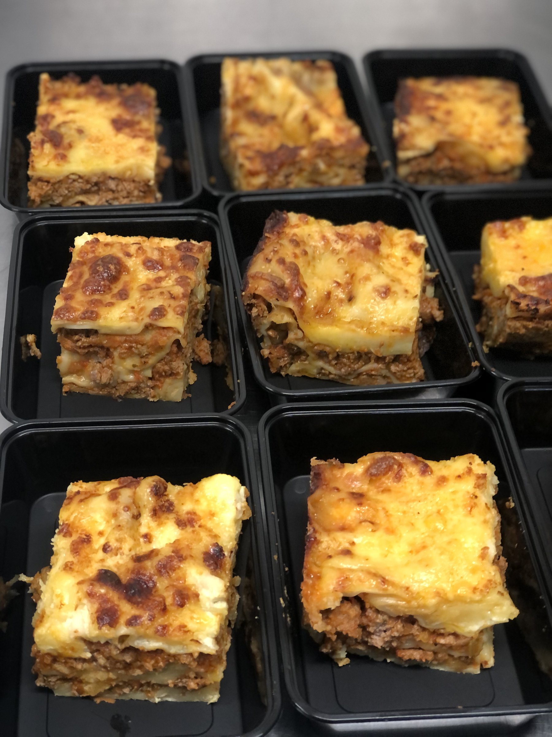 Home-cooked lasagne portions in individual takeaway containers, ready for delivery.