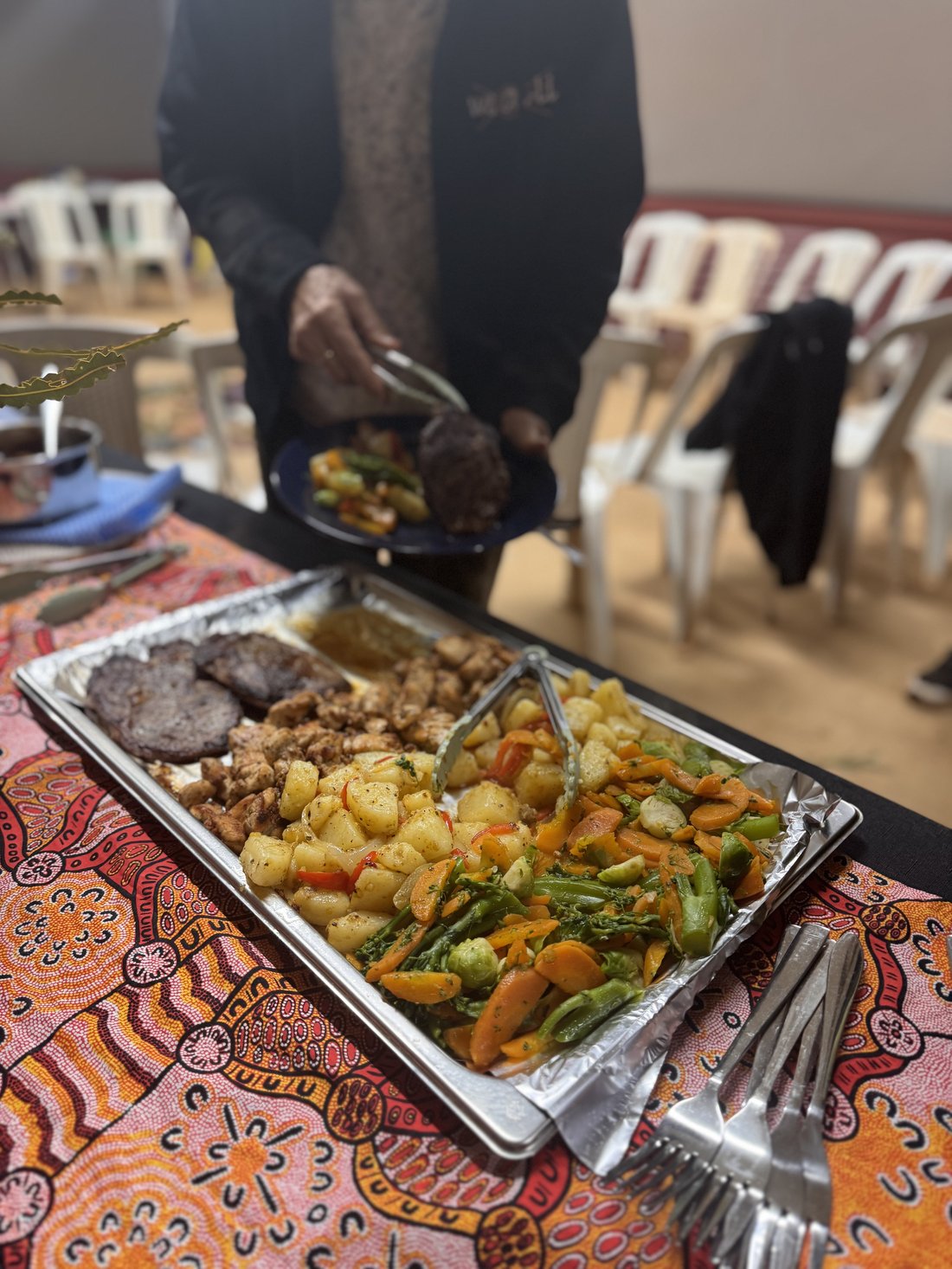 Country Heart event catering tray with steak, chicken and roast vegetables on an Aboriginal-design tablecloth.