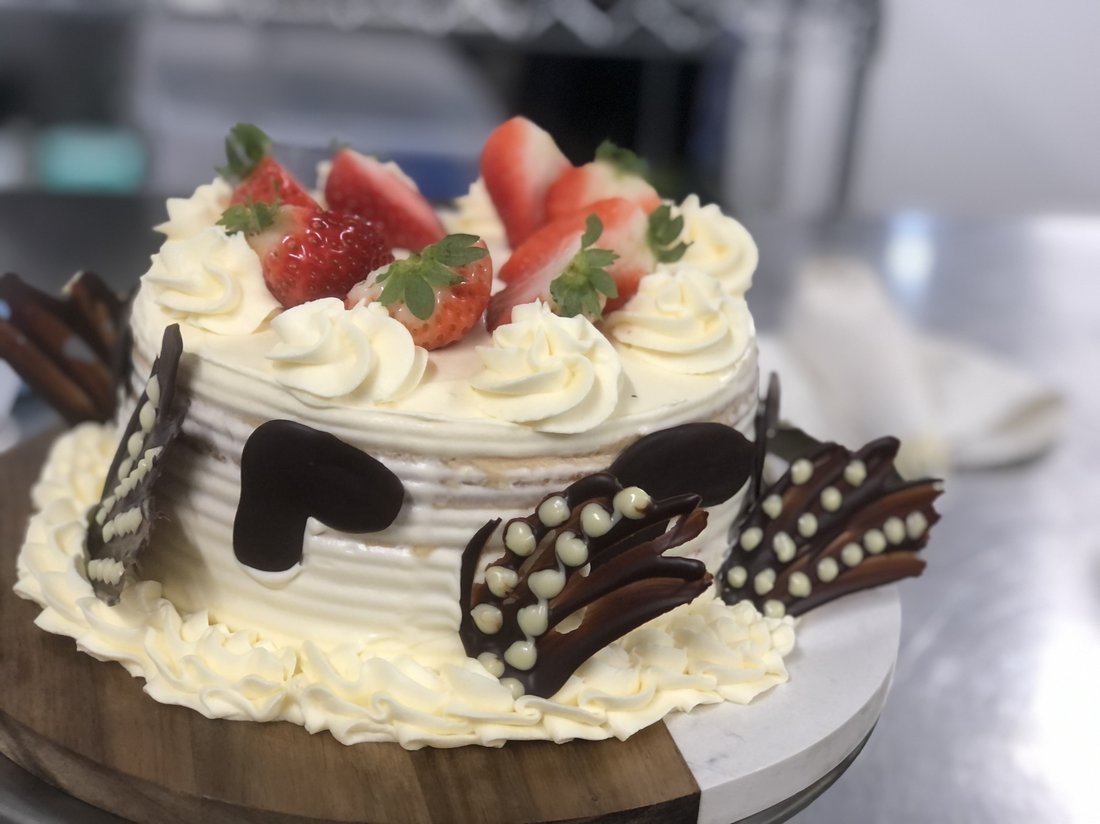 A wedding-style white cake decorated with fresh strawberries.