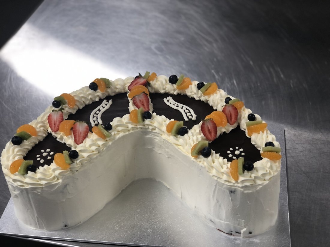 Heart-shaped white cake decorated with fruit.
