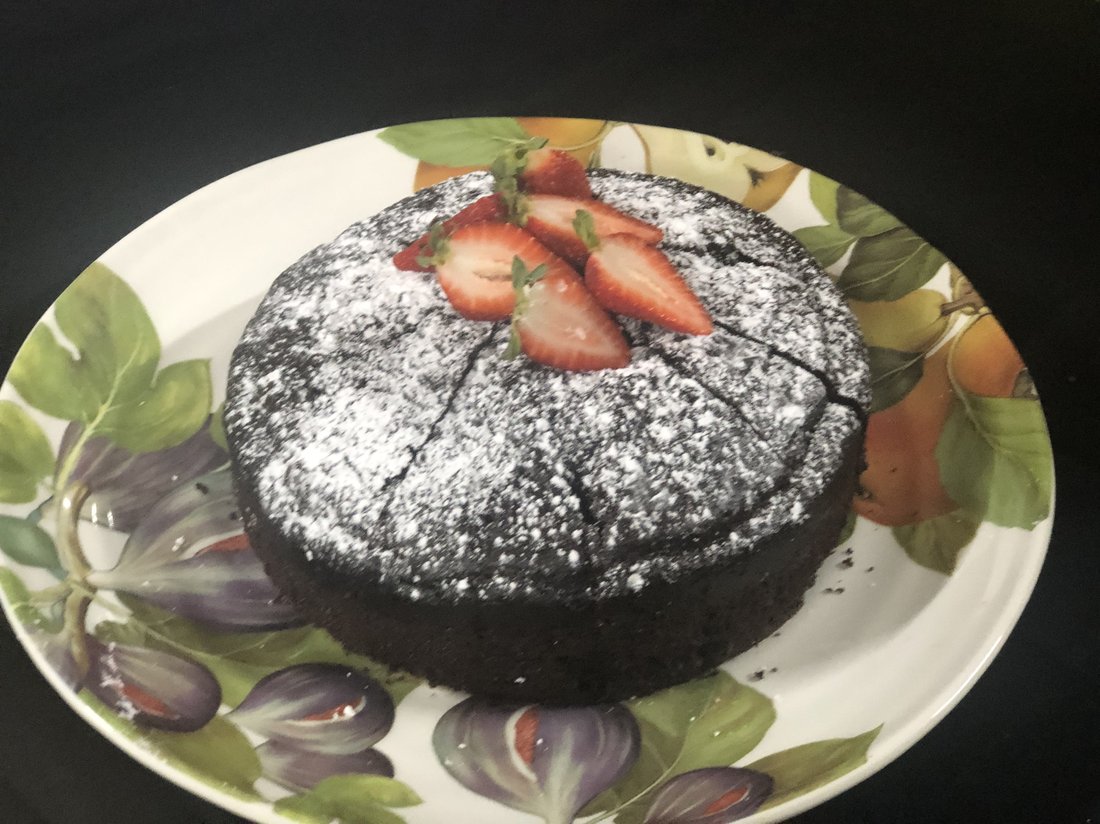 Chocolate cake topped with strawberries and icing sugar.