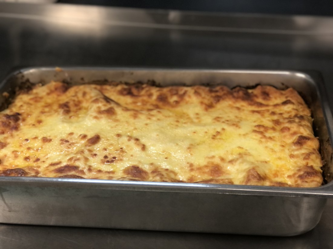 Large catering tray of golden-topped lasagne.