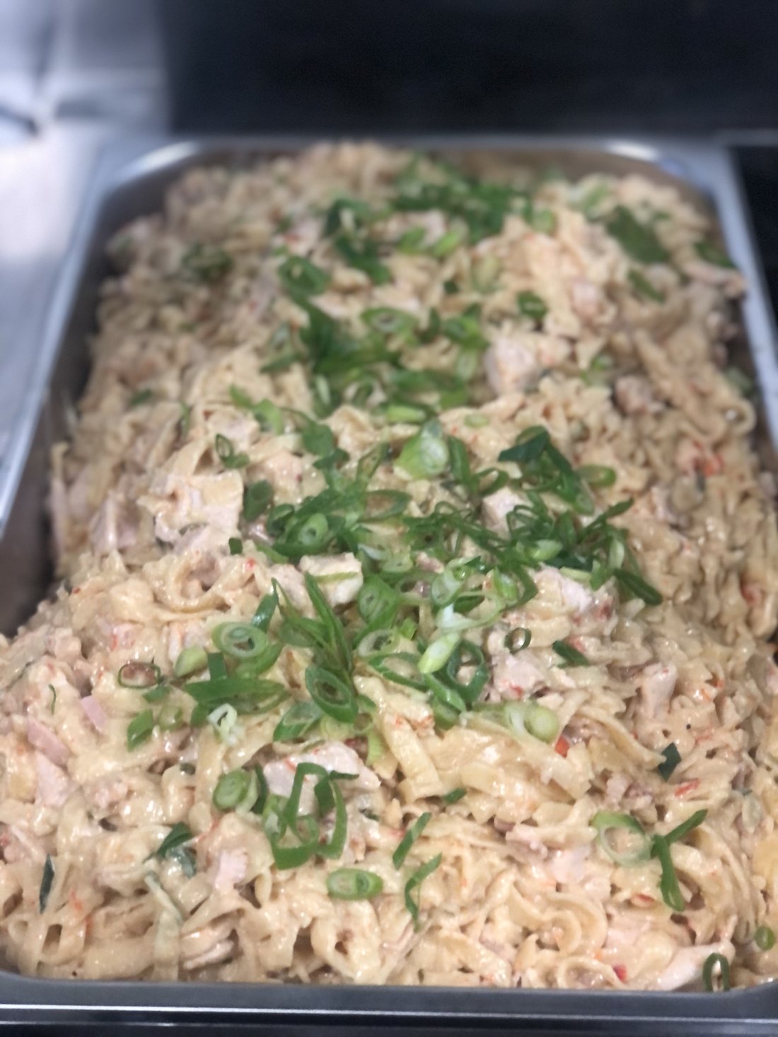 Coronation chicken catering tray topped with spring onion.