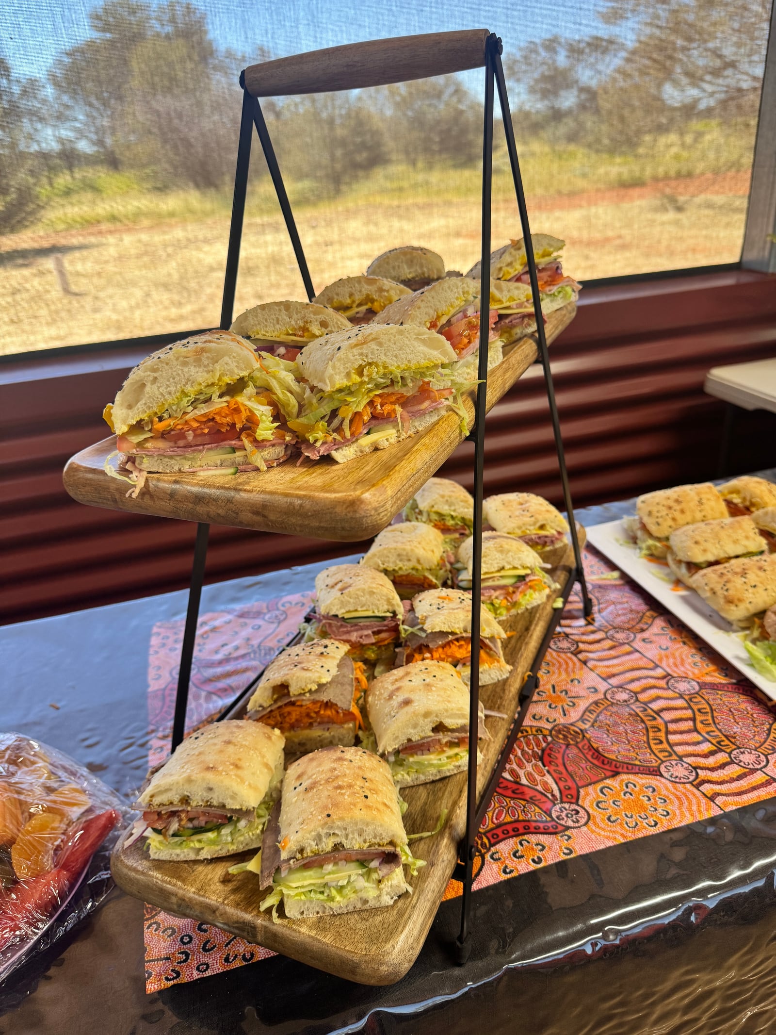 Stacked boards of fresh sandwiches at a catered event.