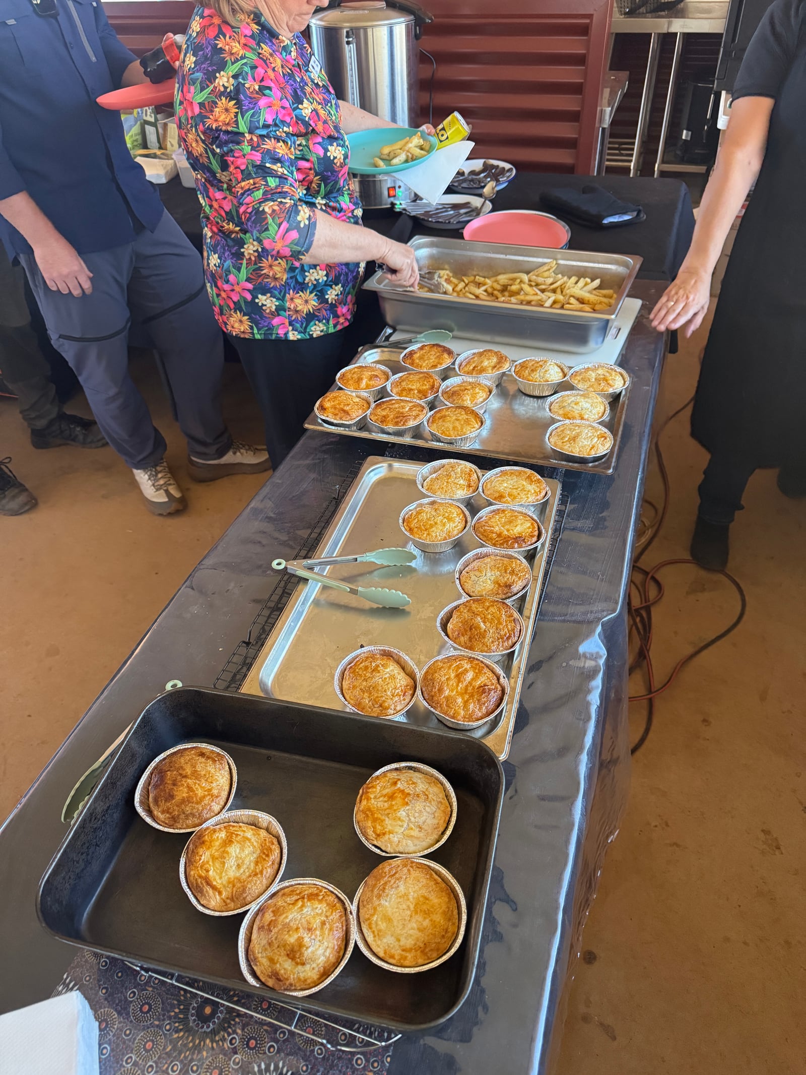 Mini pies and hot food arranged on a buffet table.