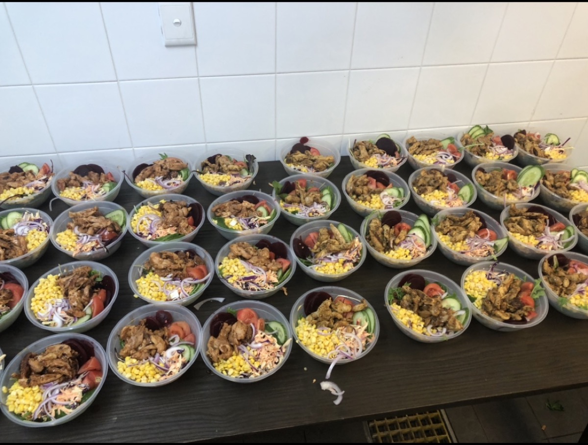 Prepared salad bowls lined up for remote community meal delivery.